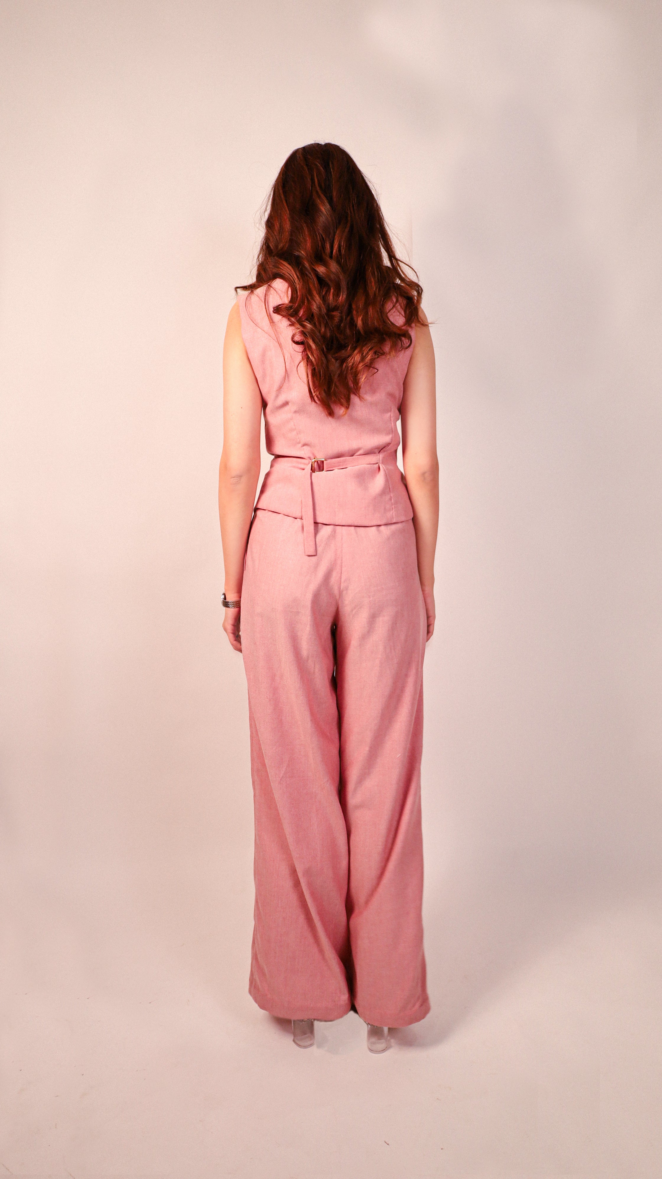 Person wearing a high-quality pink sleeveless top and wide-leg pants on a plain back view background