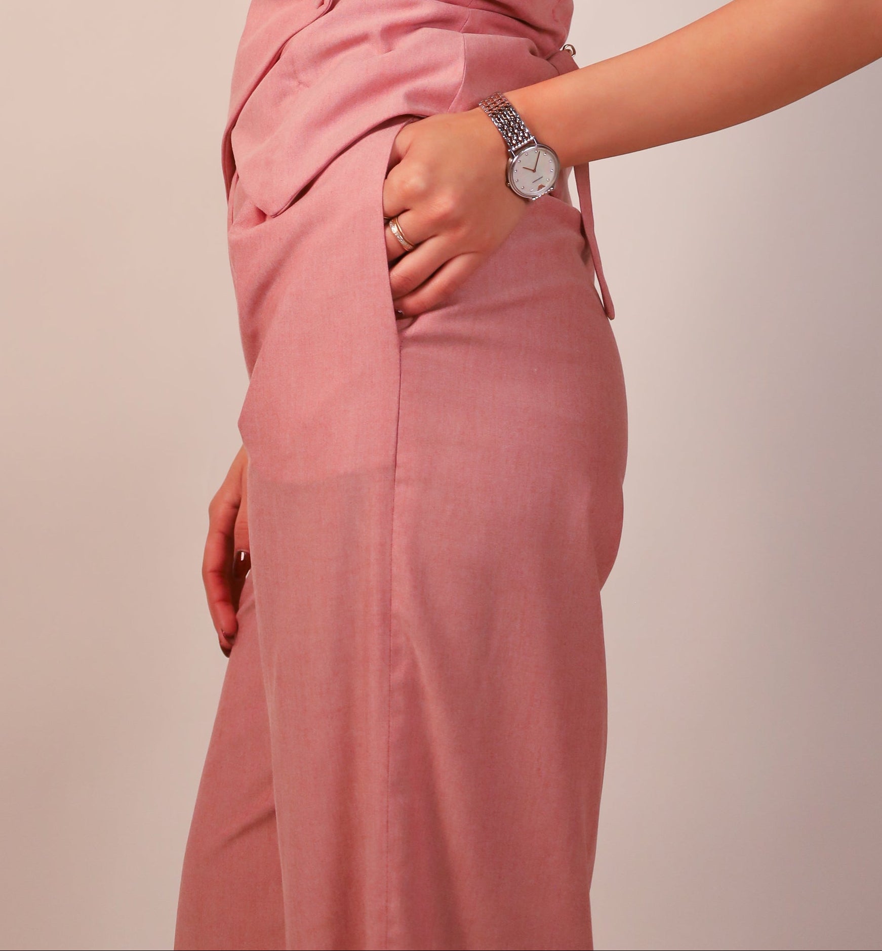 Elegant wide-leg office pants with front pleats and side pockets Woman wearing a pink sleeveless dress against a plain background side view